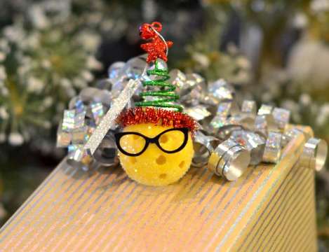 Mini Elf with Tree Hat Christmas Pickleball Ornament on top of gift box